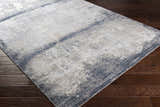 Close-up of the Rainworth Modern Slate Luxe Rug on dark wood floor. Charcoal, beige, and gray contemporary rug. Corner
