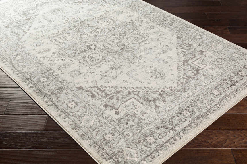 Close-up of the Rockfall Area Rug. Charcoal and gray traditional pattern on a light beige background. Corner