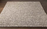 Close-up of the hand-woven Rockfield Clearance Rug. Cream and black wool rug with a nubby texture on dark wood floors. Front