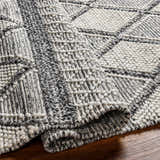 Close-up of the hand woven Rehn Area Rug showing its dark gray, light gray, and taupe geometric pattern and textured recycled PET yarn. Fold