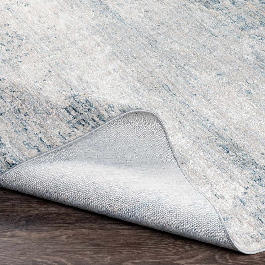 Close-up of the Rendlesham Luxe Rug showing its cream, gray, and teal abstract design and woven texture. Fold
