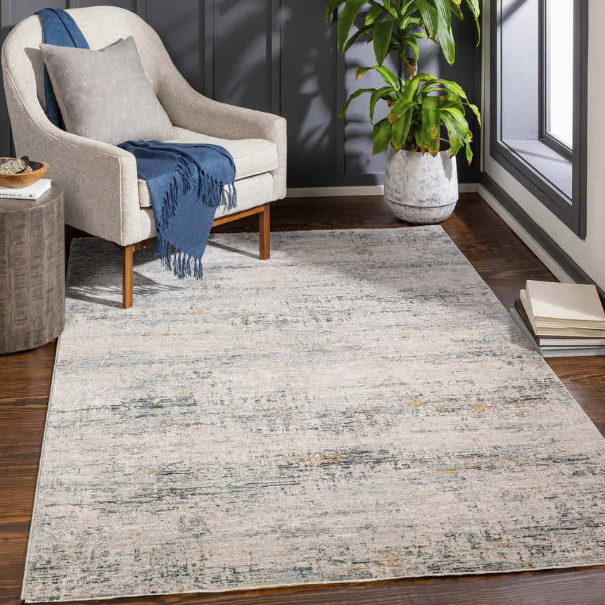 Living room scene with a Rendlesham Luxe Rug in cream, dusty sage, and gray under a chair with a blue throw. Roomscene-Rectangle