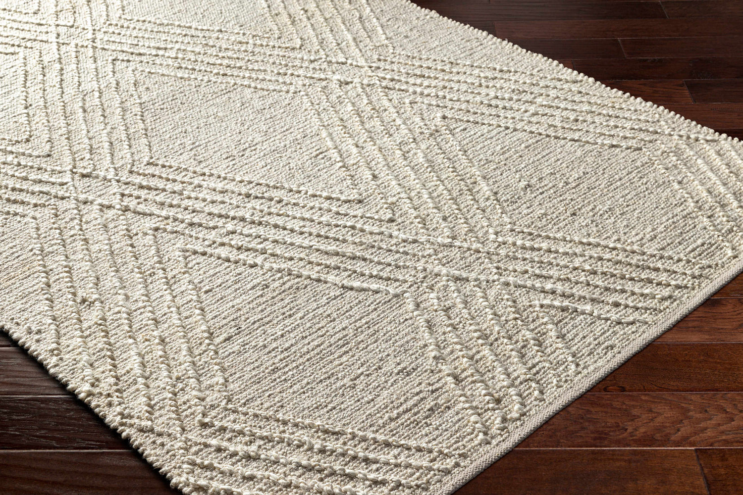 Close-up of the Renz Area Rug, a beige jute rug with a raised geometric diamond pattern. Corner
