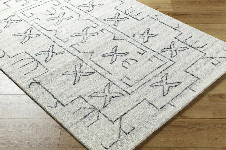 Close-up of the Rider Area Rug. Light silver, off white, and white wool rug with a contemporary geometric pattern. Corner