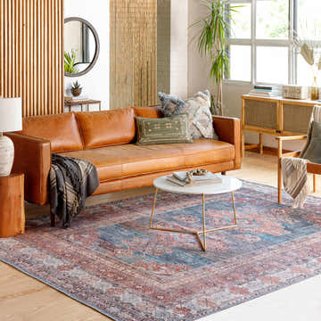 Living room scene with a Baltinglass Rust & Blue Washable Area Rug, leather sofa, and round marble coffee table. Roomscene-Rectangle