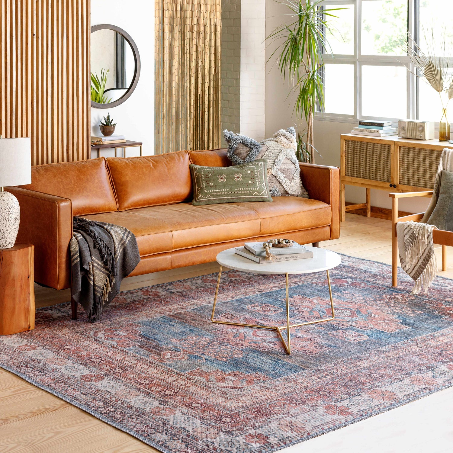 Living room scene with a Baltinglass Rust & Blue Washable Area Rug, leather sofa, and round marble coffee table. Roomscene-Rectangle