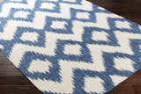 Close-up of the Oradell Blue Ikat Wool Rug with a cream and navy geometric pattern on dark wood floors. Corner