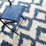 Close up of the Oradell Blue Ikat Wool Rug with a blue folding chair. Cream and navy contemporary rug pattern. Styleshot