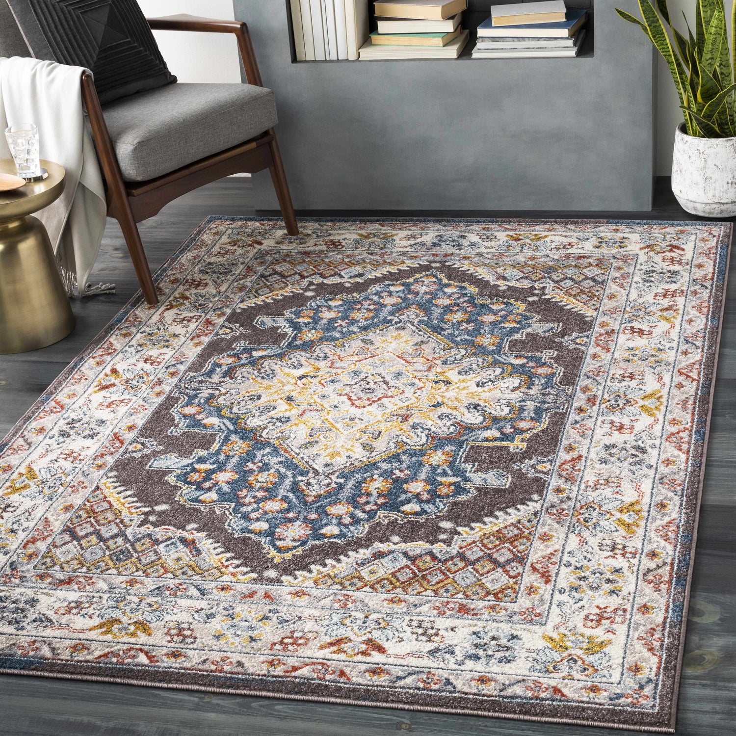 Living room scene with a Haymond Brown Medallion Area Rug, gray chair, gold side table, and dark wood floors. Roomscene-Rectangle