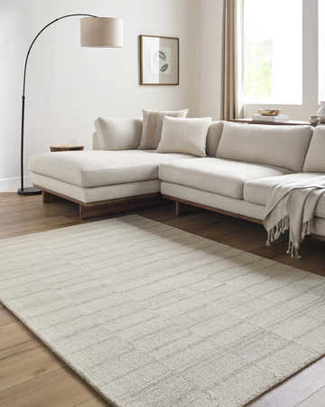 Living room scene with a neutral sectional sofa and the ash colored Onika Modern Wool Rug. Roomscene-Rectangle