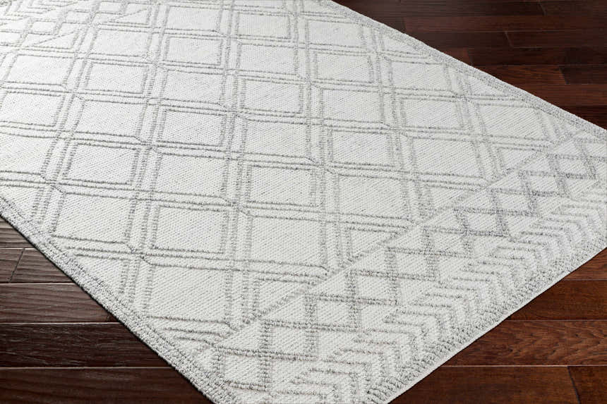 Close-up of the Rena Area Rug in arctic stone and gray, featuring a geometric diamond pattern and hand-woven texture. Corner
