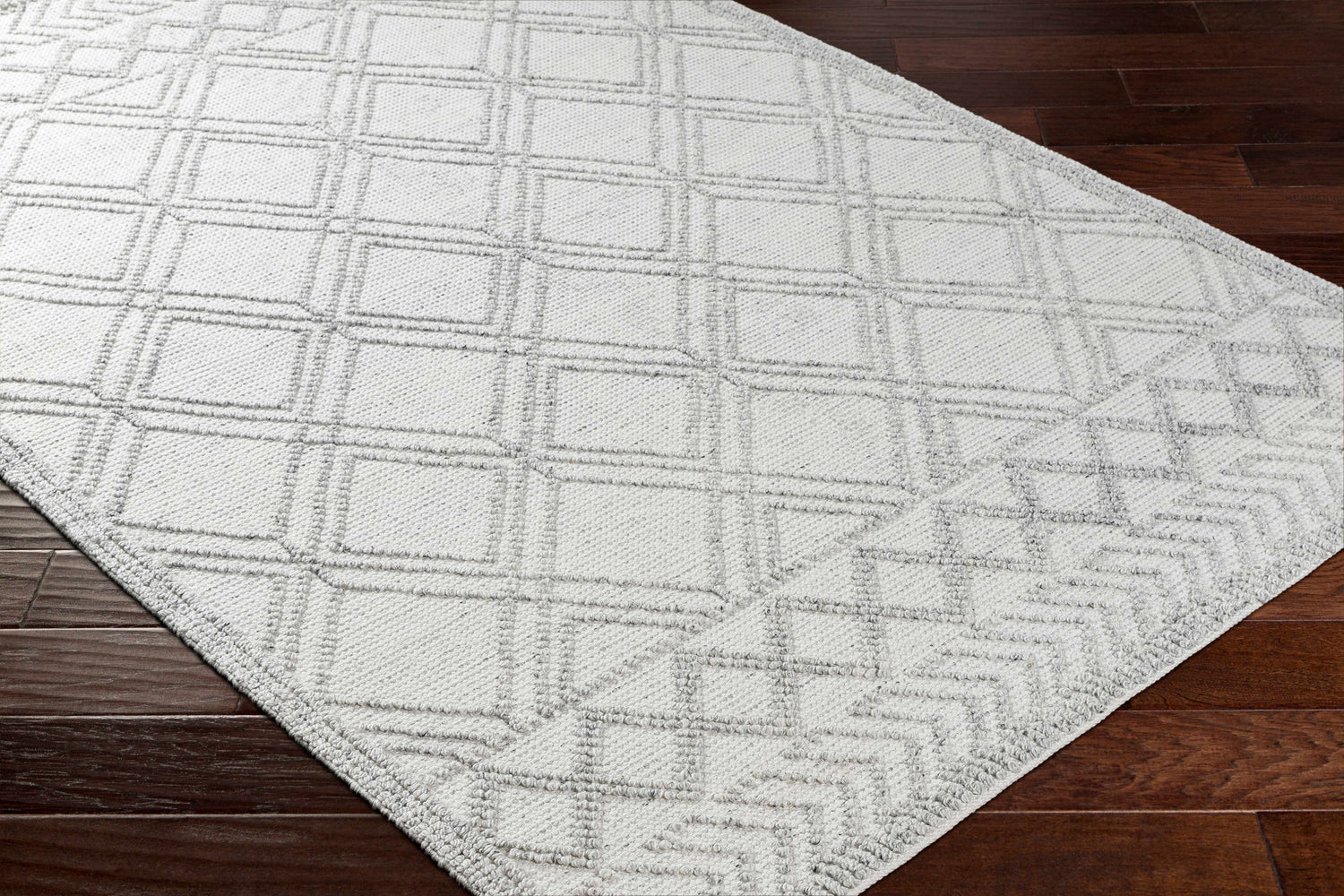 Close-up of the Rena Area Rug in arctic stone and gray, featuring a geometric diamond pattern and hand-woven texture. Corner