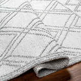 Close-up of the hand woven Rena Area Rug. Arctic stone, gray tones, geometric pattern, and textured design. Fold