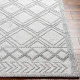 Close-up of the hand woven Rena Area Rug. Features a gray geometric diamond pattern on arctic stone recycled yarn. Front