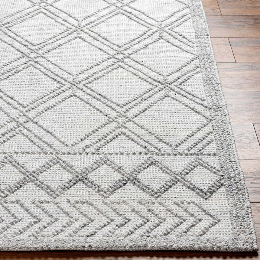 Close-up of the hand woven Rena Area Rug. Features a gray geometric diamond pattern on arctic stone recycled yarn. Front