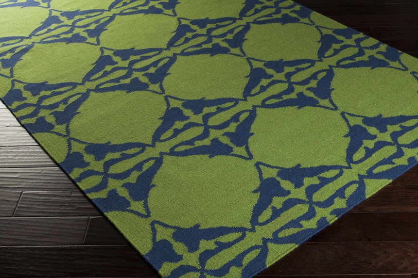 Close-up of the Rodney Area Rug. Hand-woven wool rug in grass green with a navy abstract floral pattern. Corner
