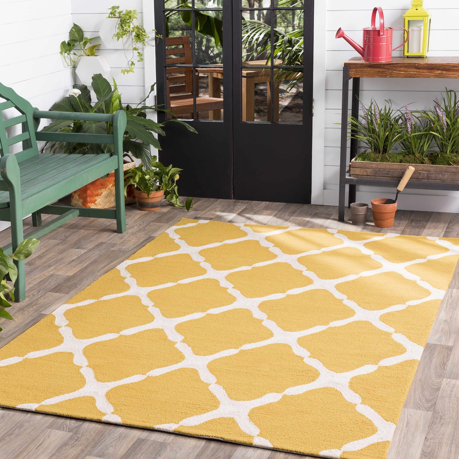 Sunroom scene with a mustard and white Roper Area Rug, green bench, and potted plants. Roomscene-Rectangle
