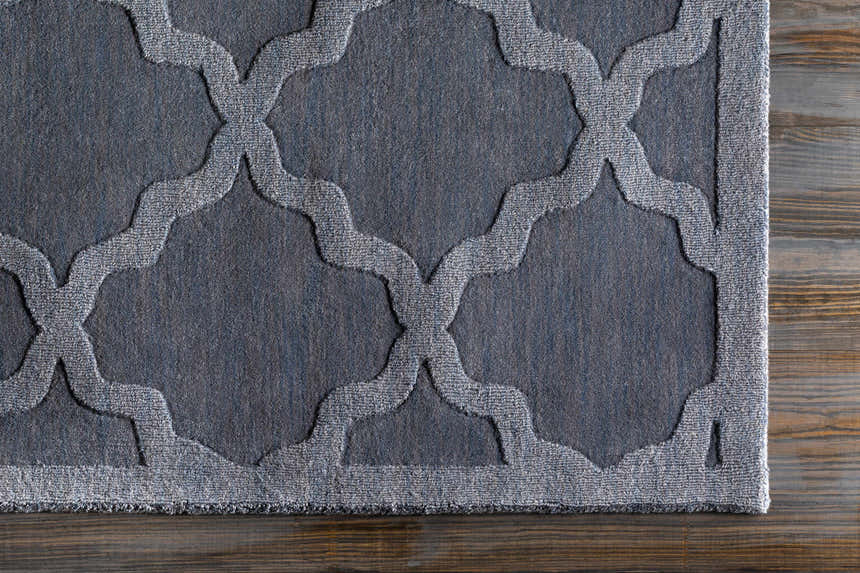 Close-up of the gray Ropesville Wool Area Rug showing its contemporary quatrefoil pattern and hand-loomed texture. Corner