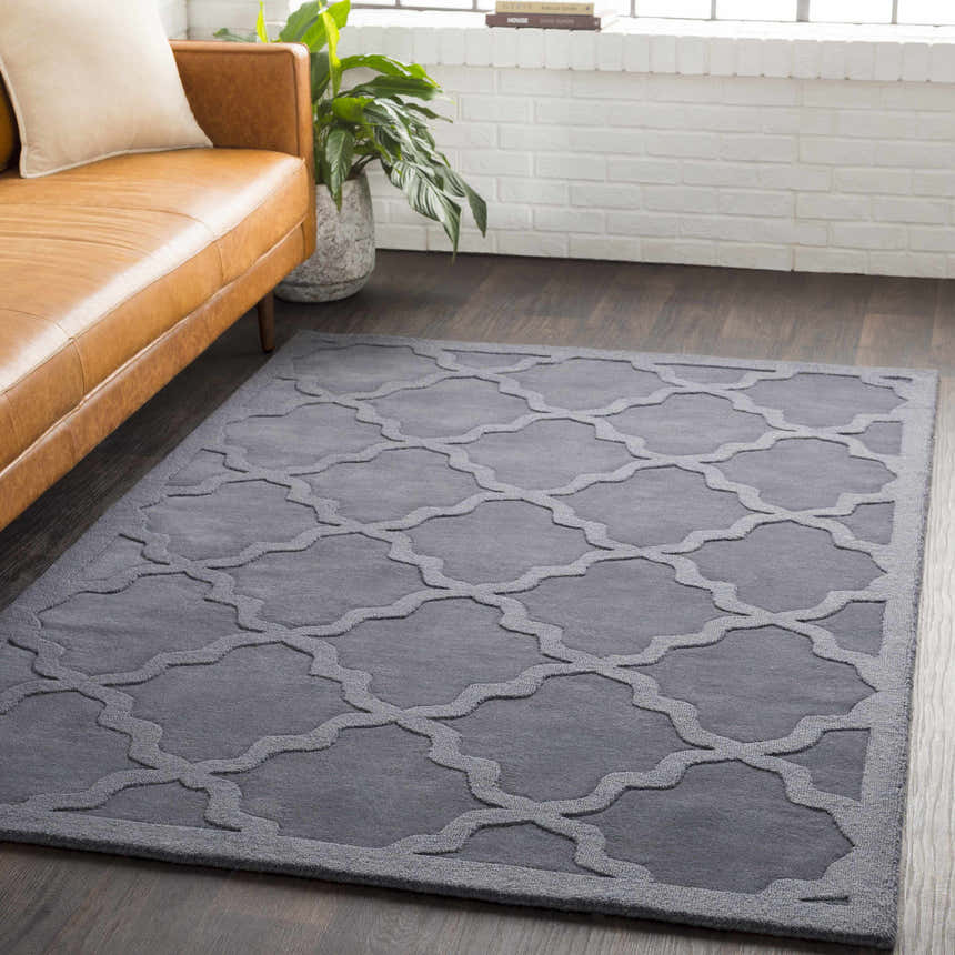 Living room scene with a gray Ropesville Wool Area Rug, tan leather sofa, and dark wood floors. Roomscene-Rectangle