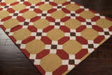 Rossiter Area Carpet on dark wood floor. Beige, burgundy, brown, and cream geometric pattern. Hand woven wool rug. Corner