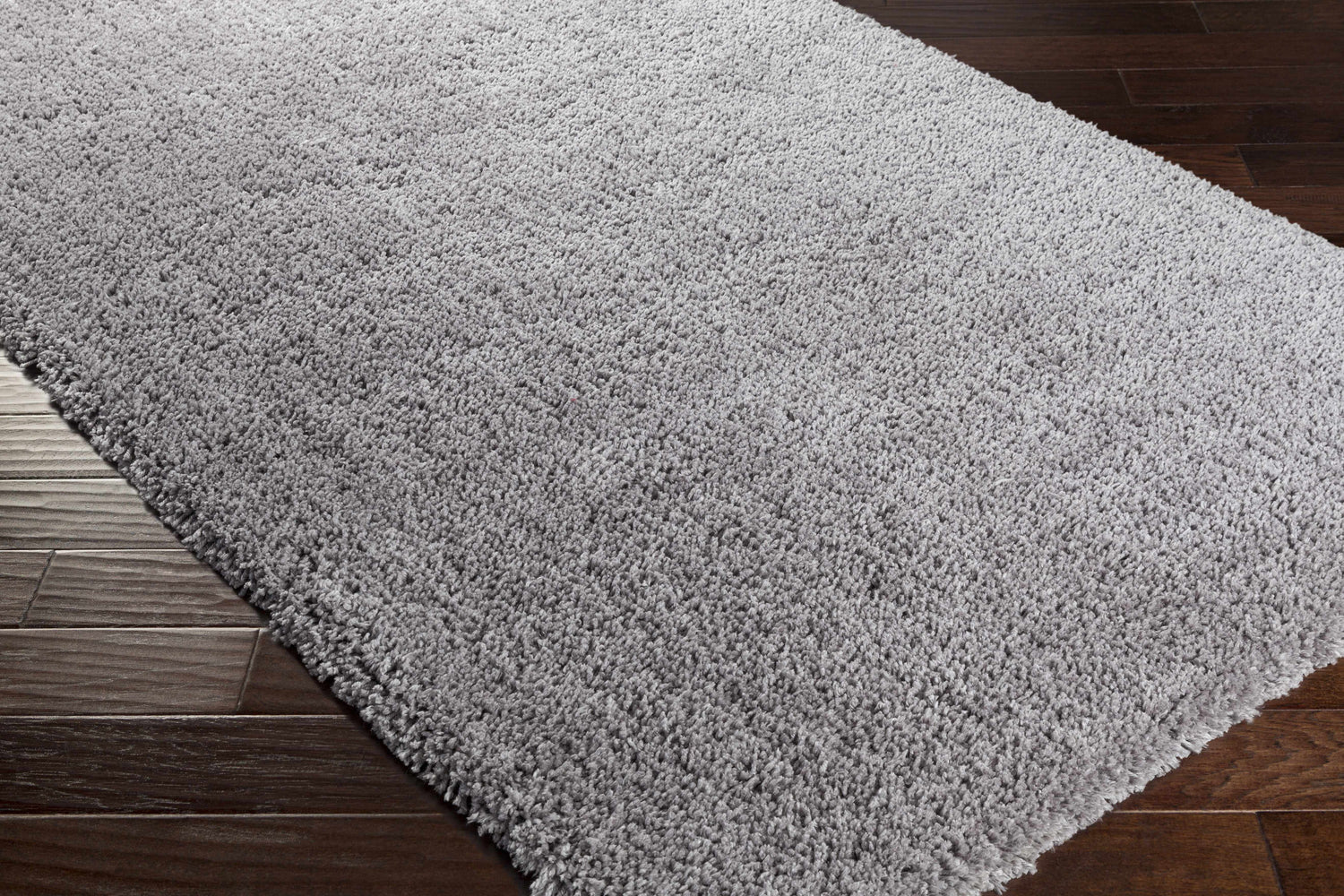 Close-up of the charcoal Tingly Solid Grey Shag Rug showing its plush texture on dark wood floors. Corner