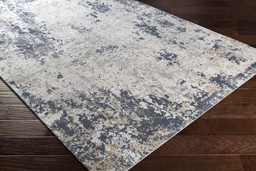 Close-up of the Ryhill Textured Luxe Area Rug in charcoal, beige, and gray on a dark wood floor. Contemporary style. Corner