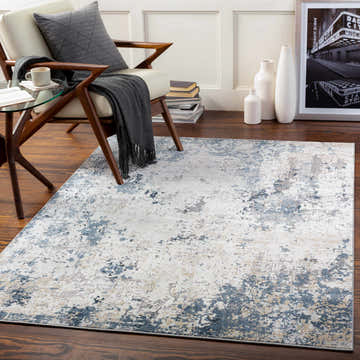 Living room scene with a Ryhill Textured Luxe Area Rug in charcoal, blue, beige, and gray tones. Modern chair and decor. Roomscene-Rectangle