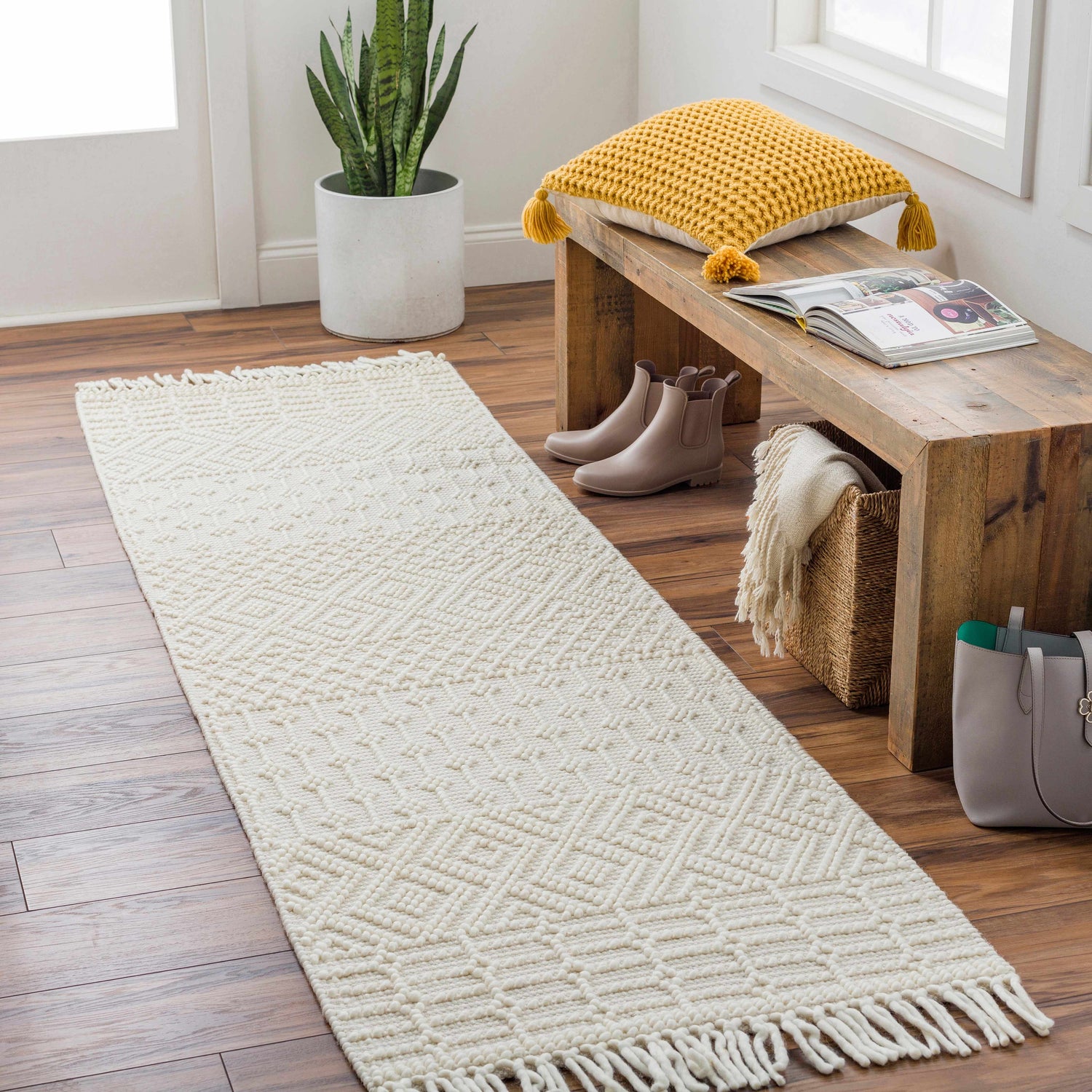 Entryway scene with a white Ryne Area Rug runner, wood bench, yellow pillow, and brown Chelsea boots. Roomscene-Runner