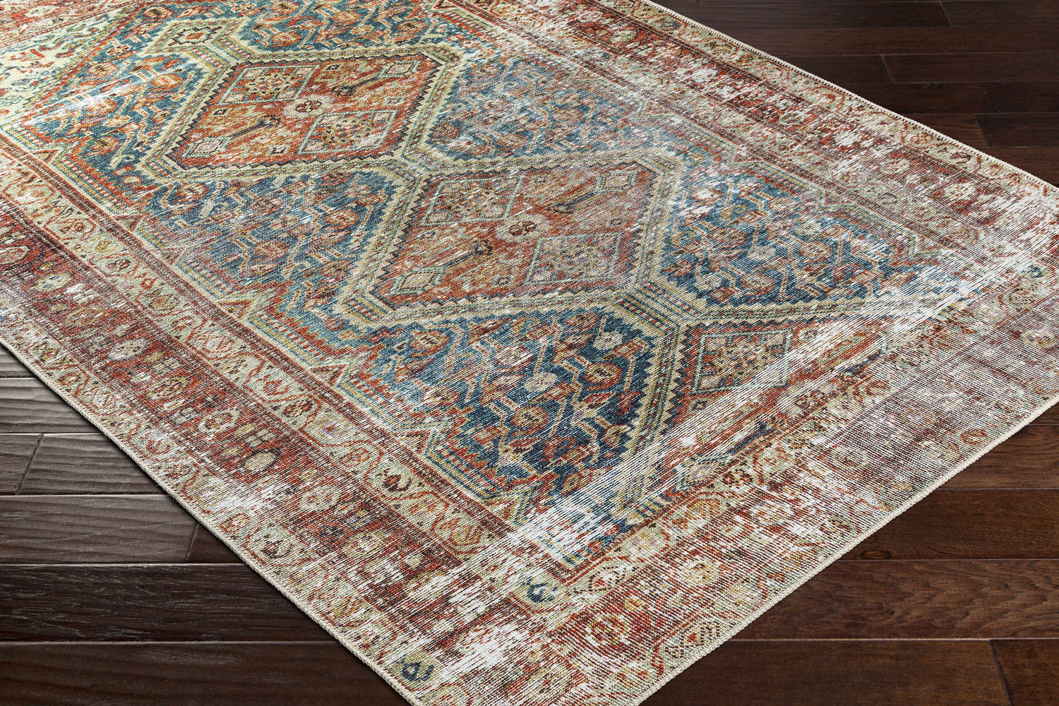 Close-up of the Rio Washable Area Rug featuring a traditional, distressed design in blue, orange, and cream. Corner