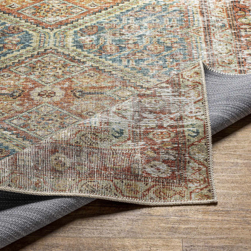 Close-up of the Rio Washable Area Rug showing its traditional, farmhouse design and colors of rust, blue, and cream. Fold