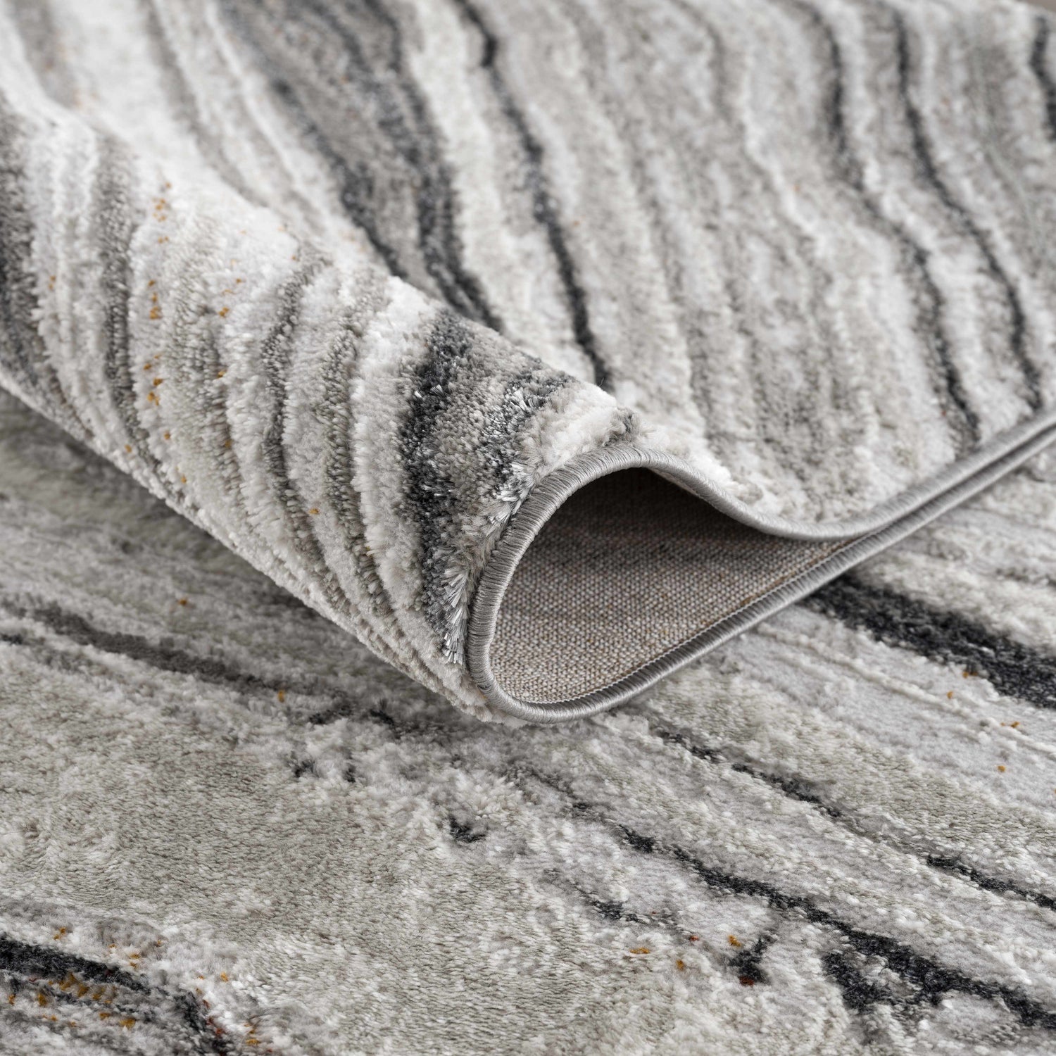 Close-up of the Live Marble Dark Gray Area Rug showing its charcoal, gray, and off-white contemporary pattern. Fold