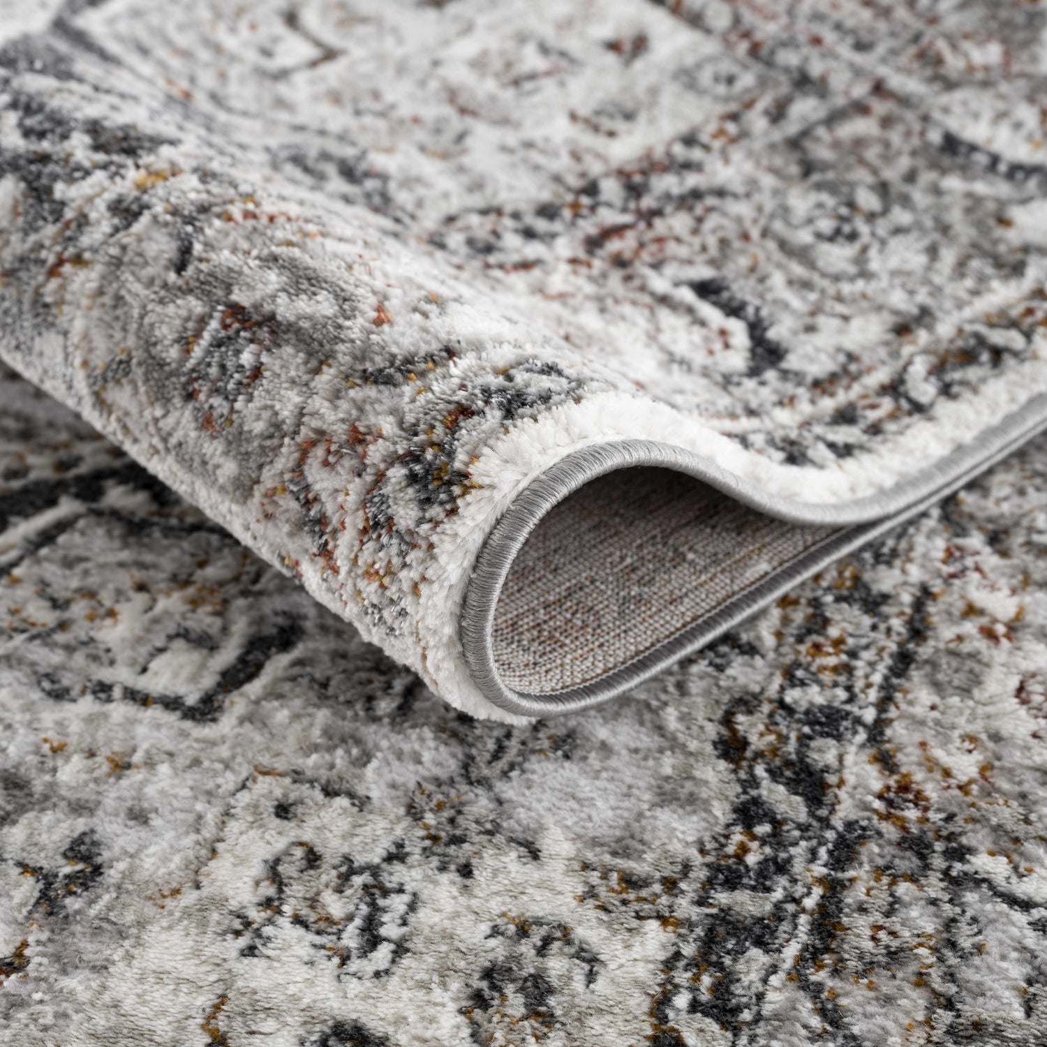 Close-up of the Liverpool Dark Gray Area Rug showing its textured, abstract design and charcoal, rust, and gray colors. Fold