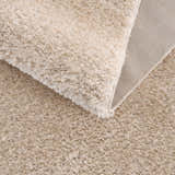 Close-up of the Heavenly Dark Beige Area Rug showing its plush shag texture and woven backing. Clearance item. Fold