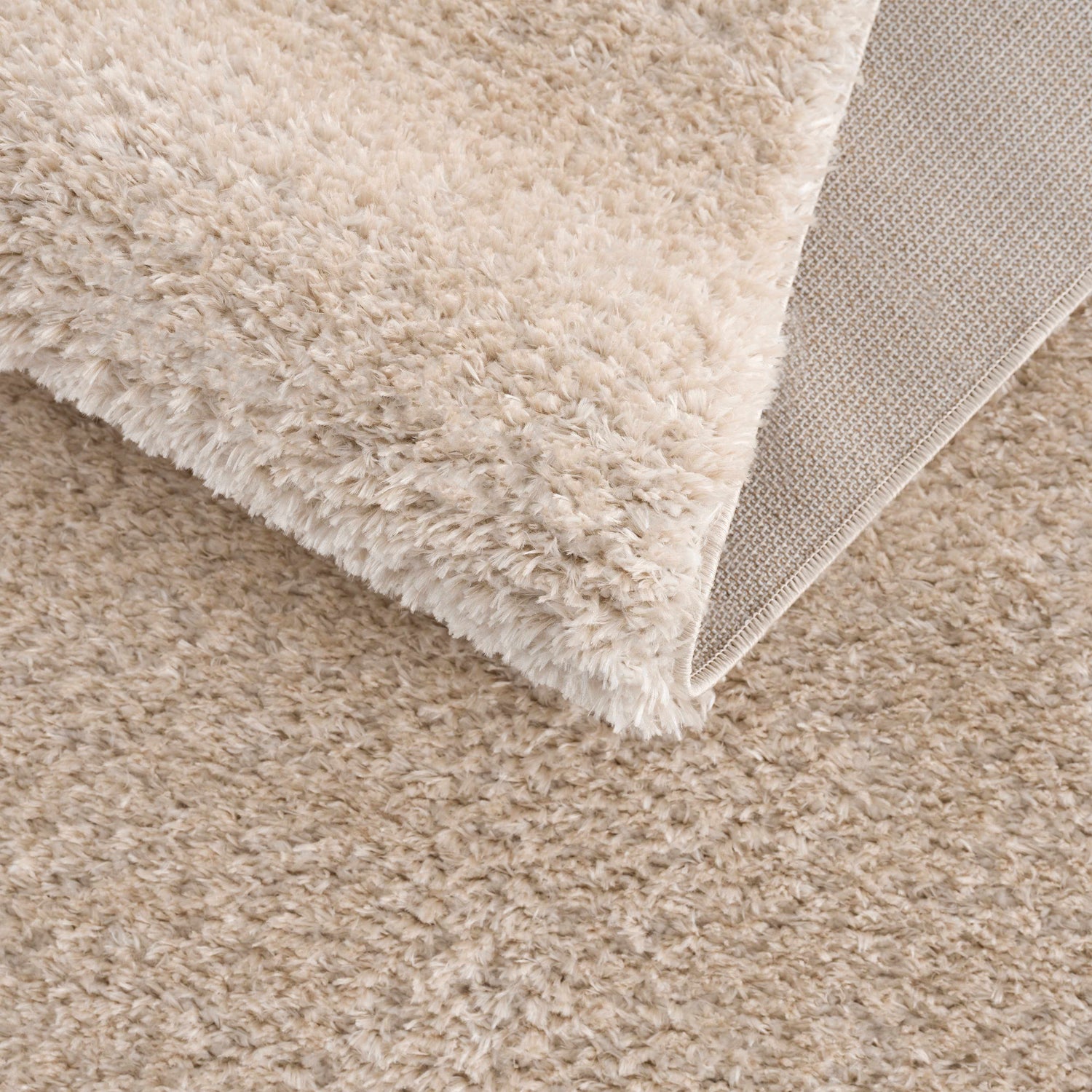 Close-up of the Heavenly Dark Beige Area Rug showing its plush shag texture and woven backing. Clearance item. Fold