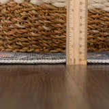 Close-up of the Rosman Distressed Washable Area Rug showing rug thickness with a ruler and a woven basket. Pile