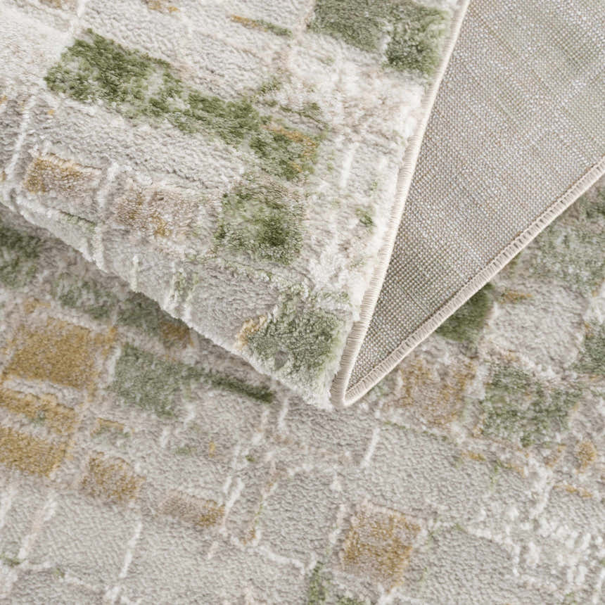 Close-up of the Liveri Green Mosaic Rug, showing its textured pile and abstract green and beige pattern. Fold