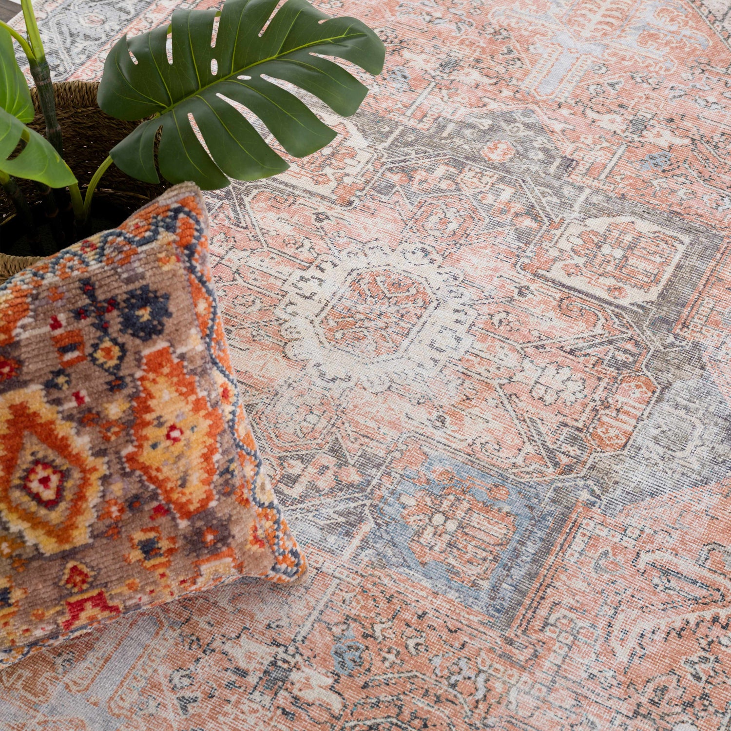 Close-up of a Rosman Distressed Washable Area Rug in beige, blue, and brick red. Oriental design with a soft, distressed texture. Styleshot