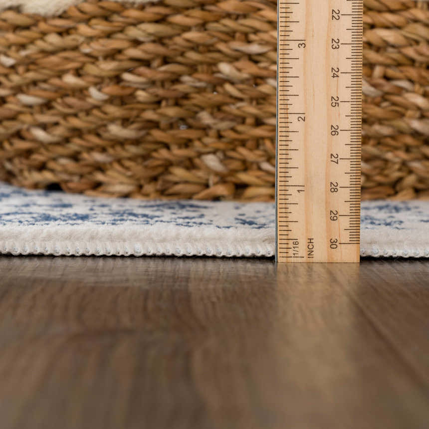 Close-up of Michie Blue Area Rug showing thickness with ruler, plus woven texture and blue and white pattern. Pile