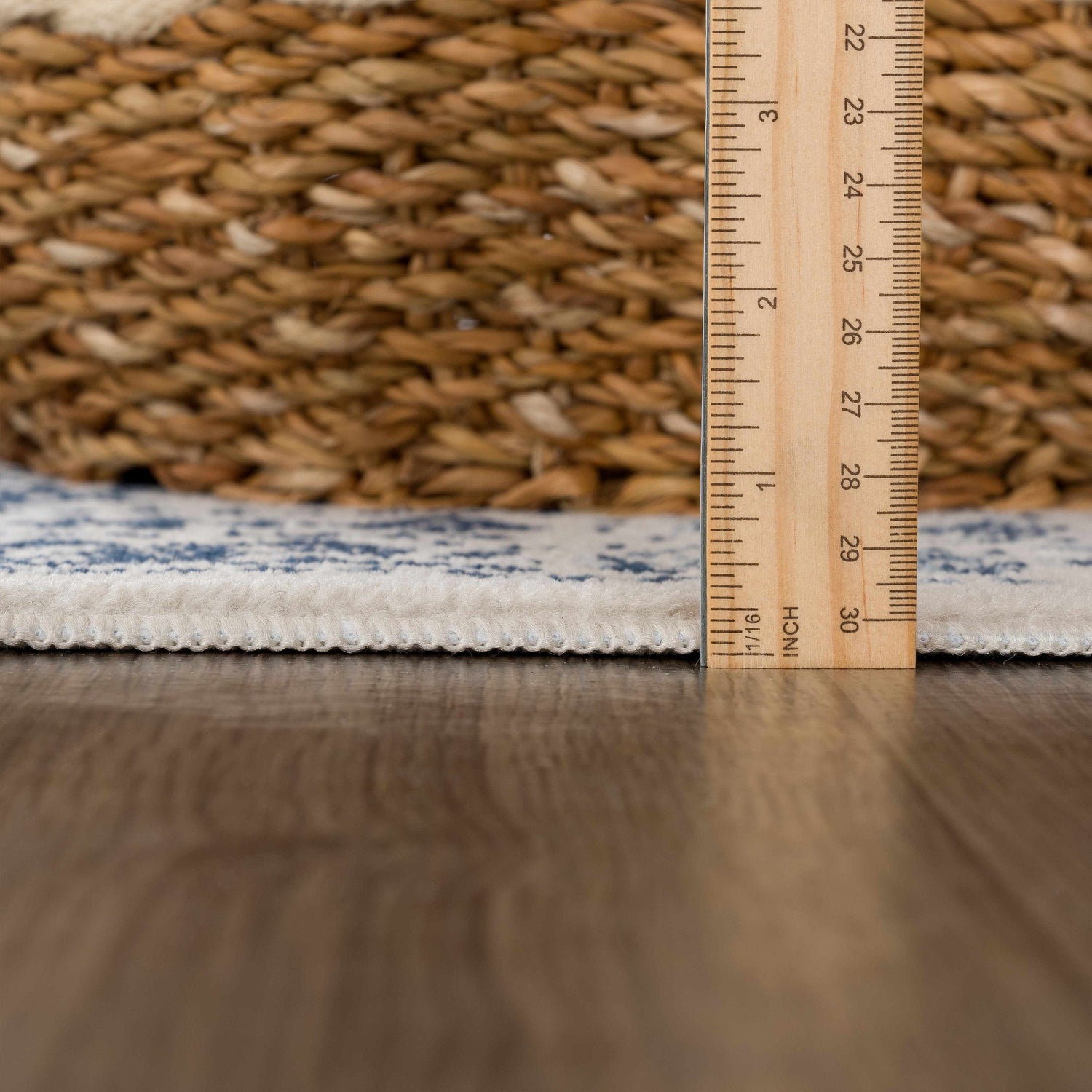 Close-up of Michie Blue Area Rug showing thickness with ruler, plus woven texture and blue and white pattern. Pile