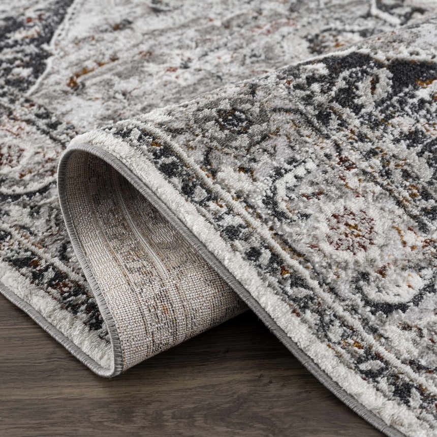 Close-up of the Liverpool Dark Gray Area Rug showing its charcoal, gray, rust, and off-white traditional pattern. Fold