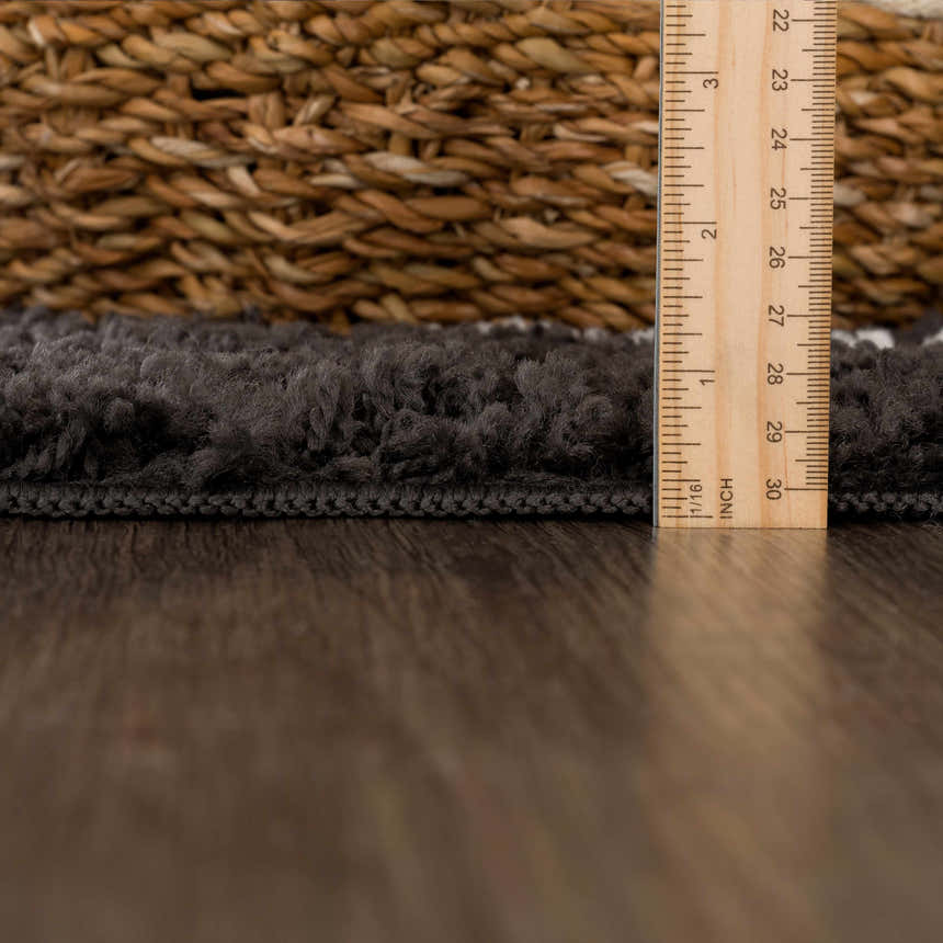 Close-up of the charcoal Ennis Area Rug showing its shag texture and thickness with a ruler for scale. Pile