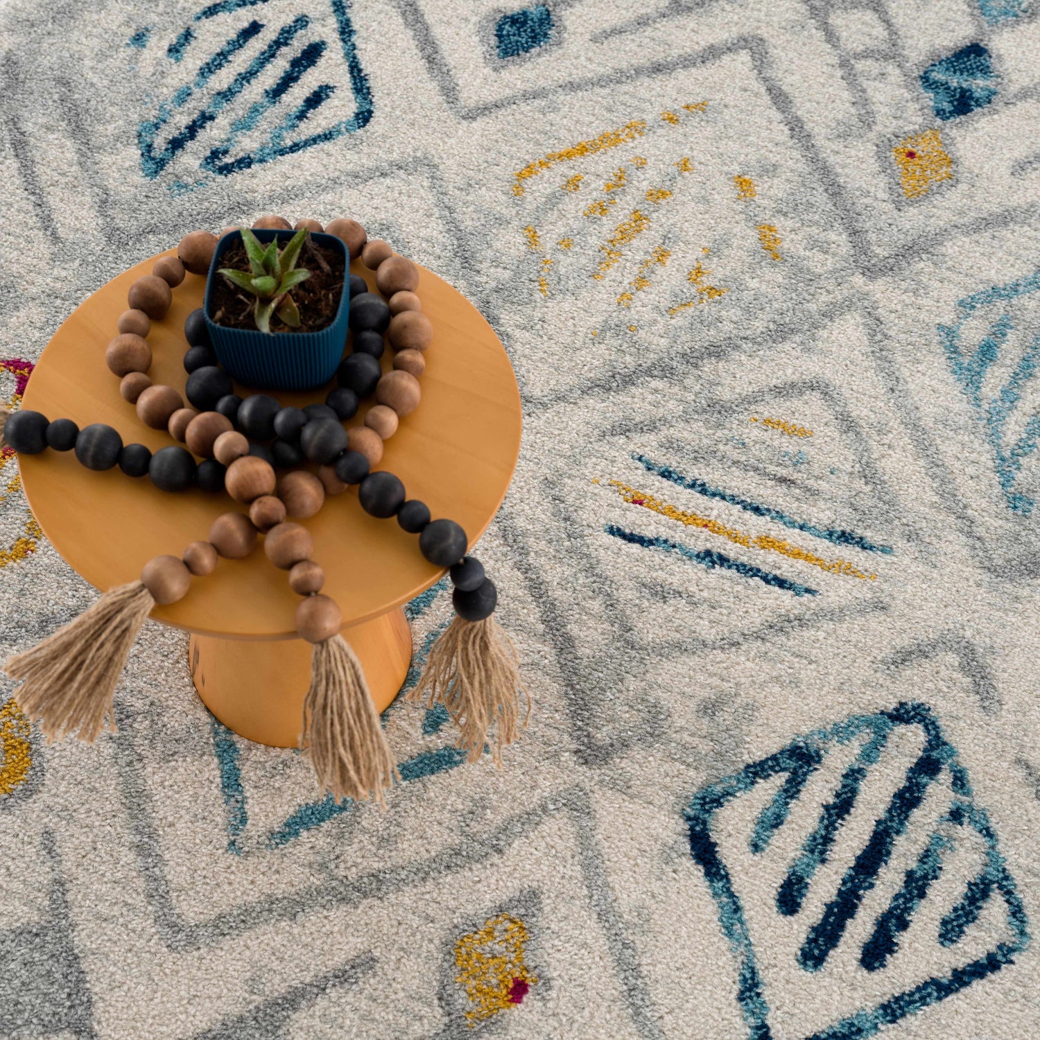 Close-up of the Istanbul Aztec Area Rug, a machine-woven rug with a geometric pattern in light gray, blue, and mustard colors. Styleshot