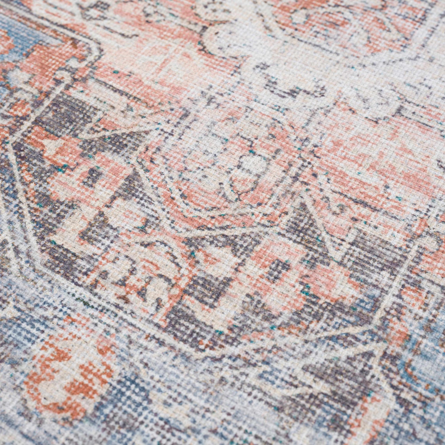 Close-up of the Rosman Distressed Washable Area Rug. Beige, blue, brick red, and gray oriental pattern with a distressed texture. Texture