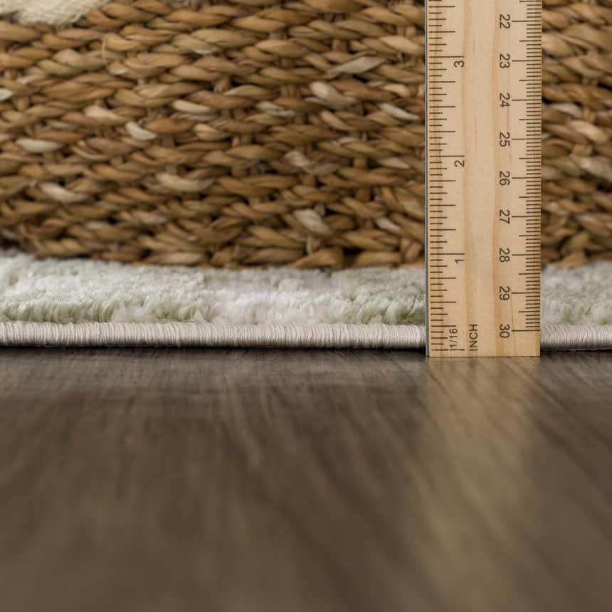 Close-up of the Liveri Green Mosaic Rug showing pile height with a ruler and a woven basket in the background. Pile