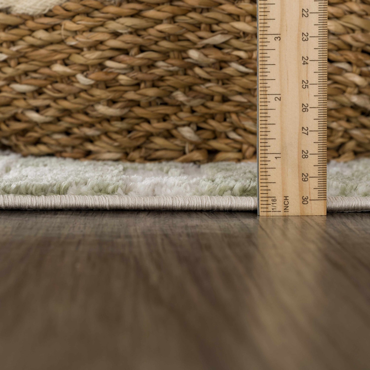 Close-up of the Liveri Green Mosaic Rug showing pile height with a ruler and a woven basket in the background. Pile