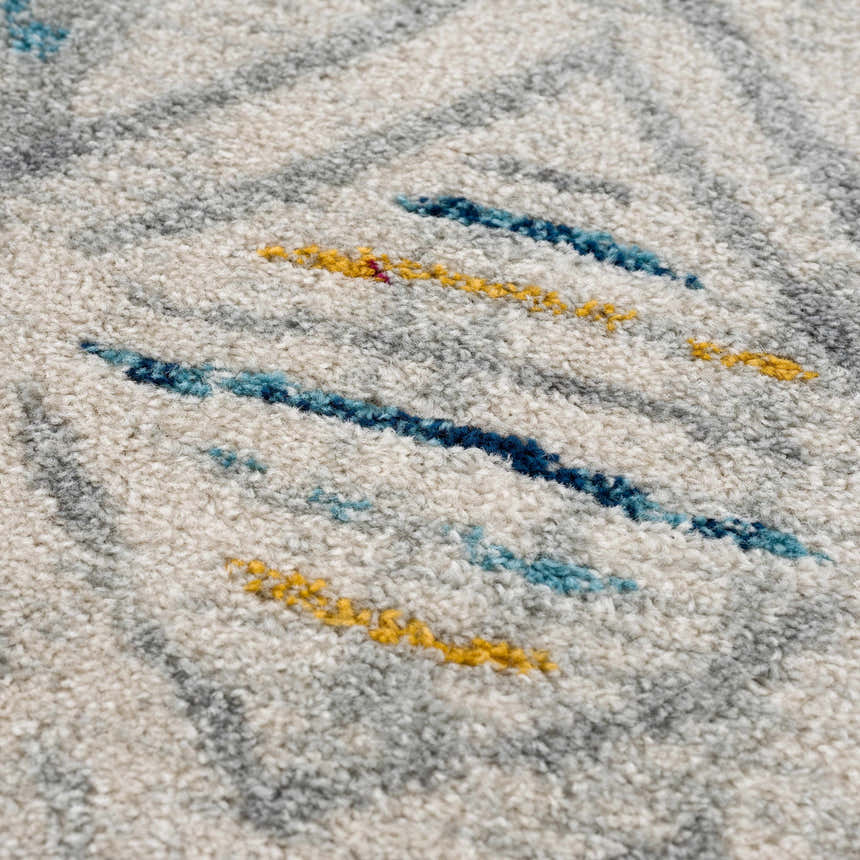 Close-up of the Istanbul Aztec Area Rug showing its off-white base with blue, gray, and mustard geometric accents. Texture