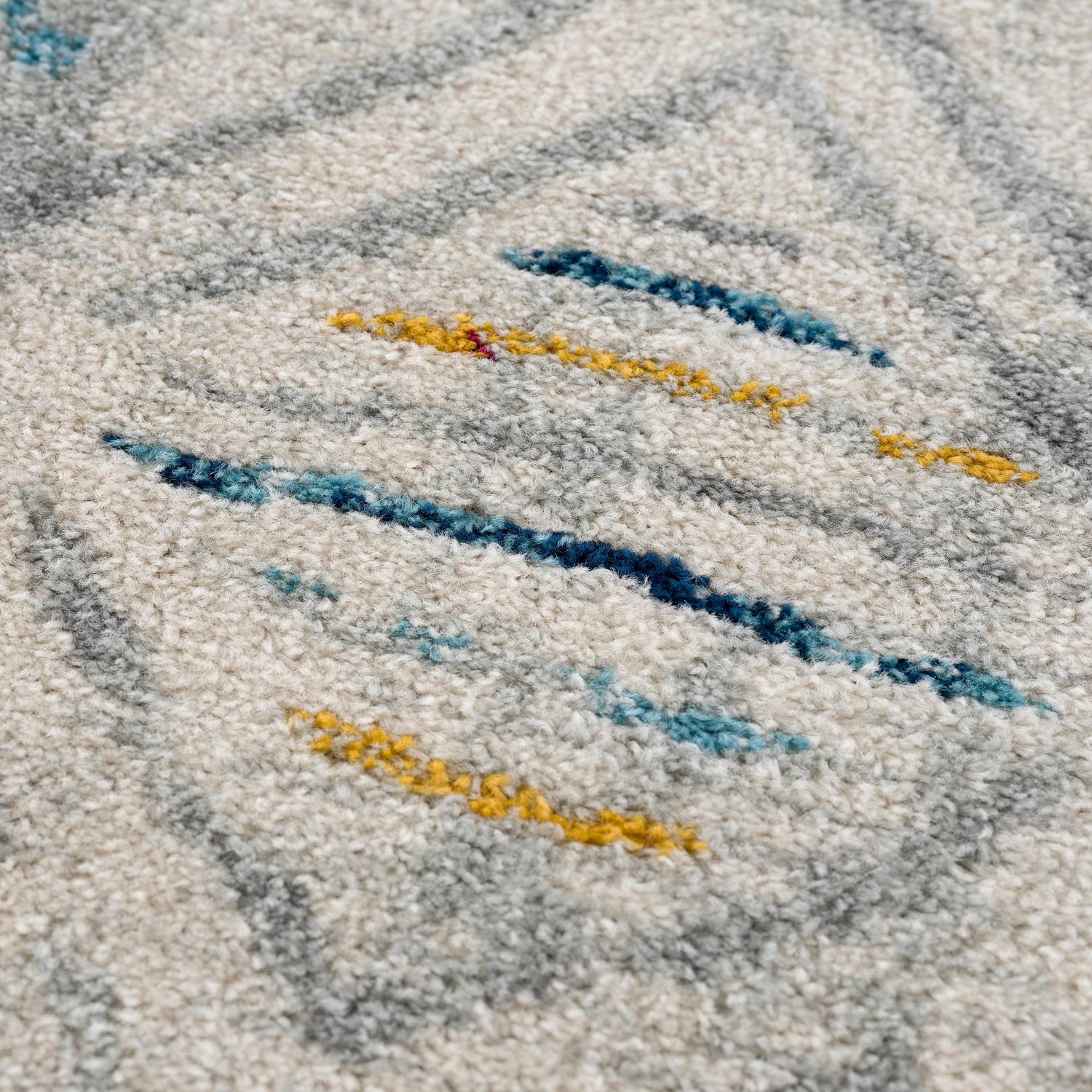 Close-up of the Istanbul Aztec Area Rug showing its off-white base with blue, gray, and mustard geometric accents. Texture