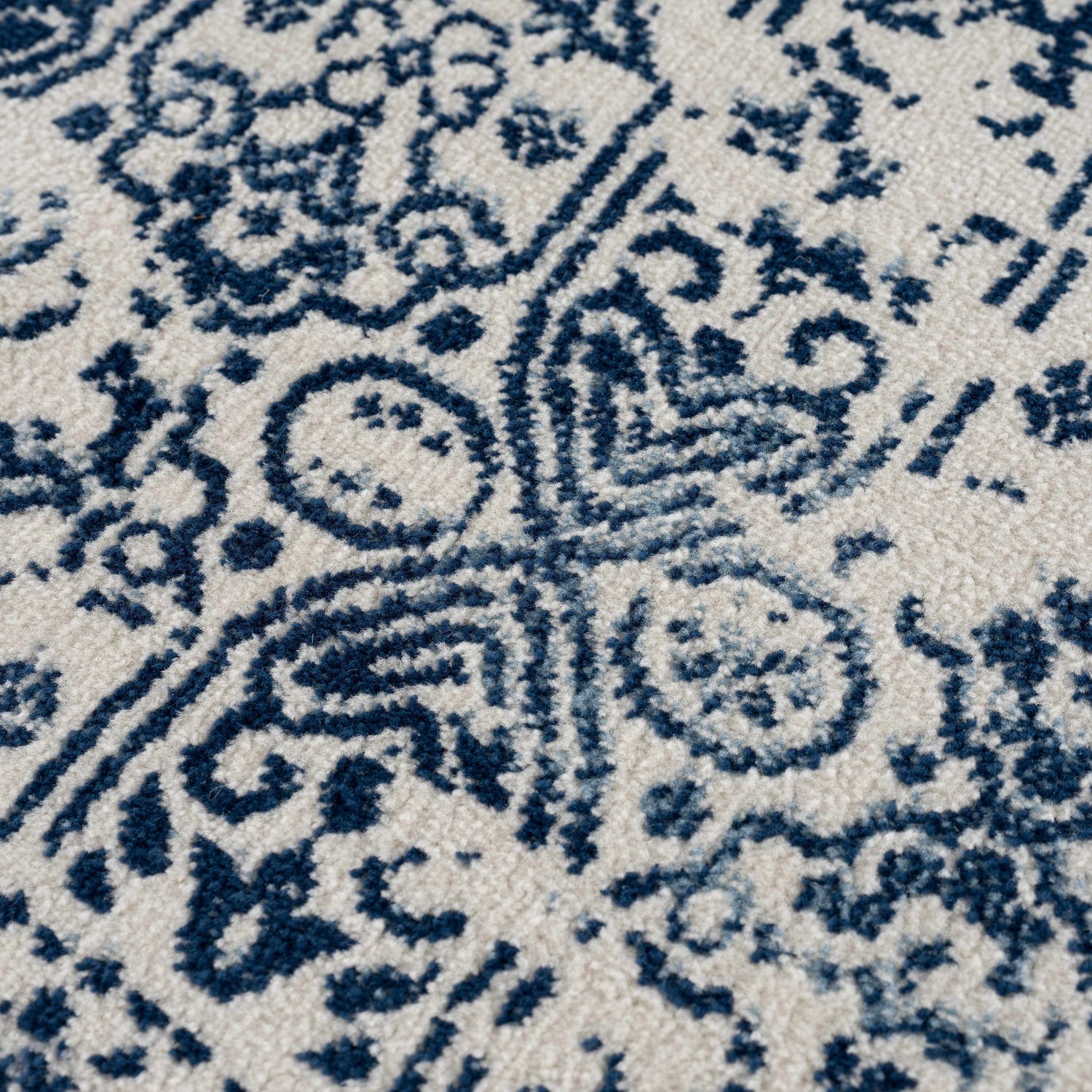 Close-up of the Michie Blue Area Rug showing its dark blue, light blue, and white Bohemian-inspired pattern. Texture