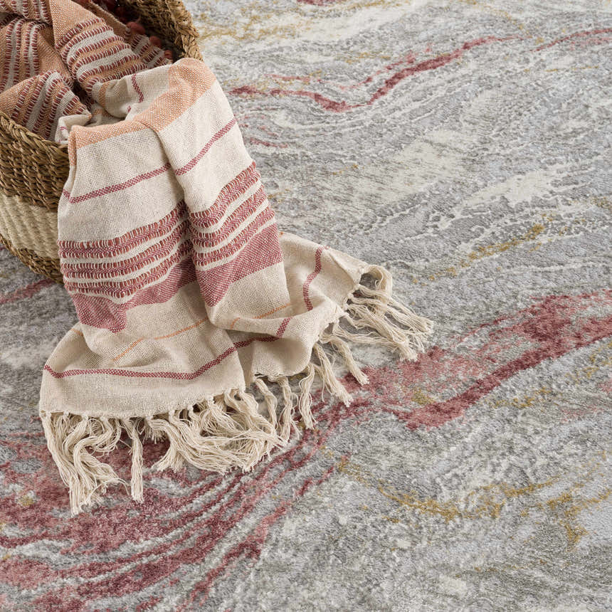 Close-up of the Lively Marble Pink Area Rug featuring a gray, pink, and mustard marble pattern with a striped throw blanket. Styleshot