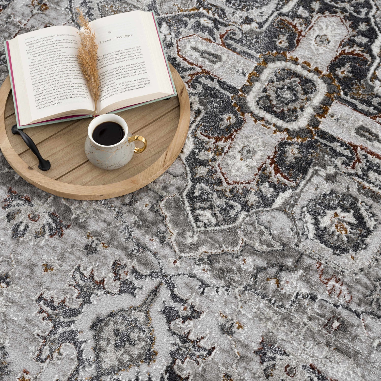 Close-up of the Liverpool Dark Gray Area Rug with a book, coffee, and decorative sprig on a wooden tray. Styleshot